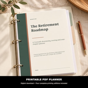 May include: A cream-coloured planner titled The Retirement Roadmap in a three-ring binder. The cover features a dark green vertical stripe, a thin terracotta line, and text describing a 12-month downsizing and next-chapter planner.