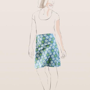 May include: Illustration of a woman wearing a blue mini skirt with a white and green daisy pattern. The woman is also wearing a white t-shirt. The image is a sketch with a neutral background.