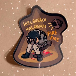 May include: A sticker depicting a stressed character in a brown and tan setting. The character is seated, with hands covering their face. Text includes "HULL BREACH" and "FIRE FIRE" in orange. A speaker is also depicted.