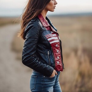 May include: Black leather jacket with a red collar and American flag design on the front. The jacket features a zipper closure and is paired with blue jeans. The jacket has a quilted pattern on the sleeves.