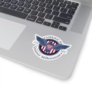 Puede incluir: Una pegatina con un diseño patriótico. Presenta un águila azul, rayas rojas y blancas y el texto "America Quarter Millennium 1776-2026". La pegatina es blanca con un acabado brillante.