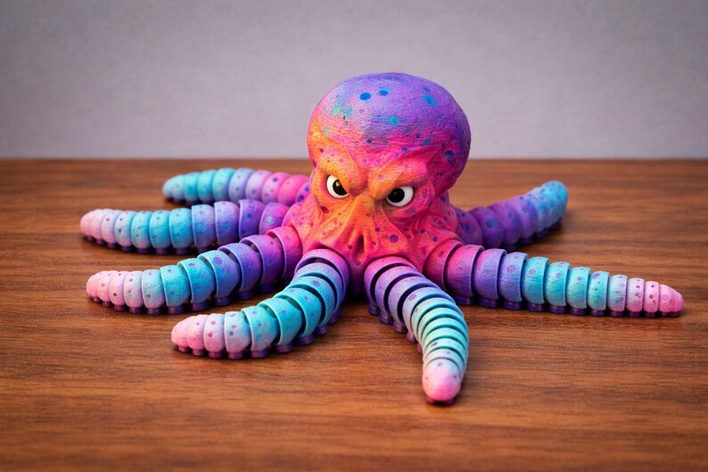 May include: A colorful, stylized octopus figurine with a vibrant gradient of pink, purple, blue, and orange hues. The octopus has segmented tentacles and an expressive face, set against a wooden surface.