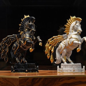 K&ouml;nnte beinhalten: Zwei dekorative Pferdestatuen, eine schwarze und eine wei&szlig;e, mit goldenen Akzenten. Die gefl&uuml;gelten Pferde stehen auf dekorativen Sockeln. Die Statuen sind aufb&auml;umend dargestellt und zeigen komplizierte Details.