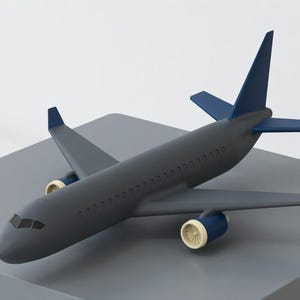 May include: A gray airplane model with blue accents on the tail and wings, and cream-colored engine details. The toy airplane is positioned on a gray surface, showcasing its design.
