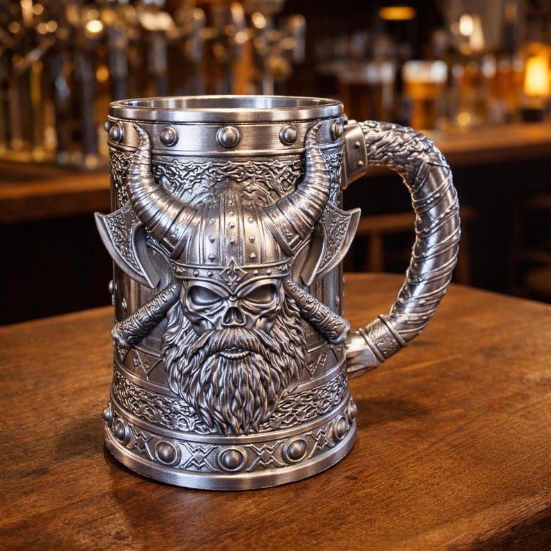 A professional collage showcasing over 20 unique 3D printable STL models for beer mugs and can holders. The image features high-detail designs including a horned Minotaur with gold accents, a gothic skull wearing aviator goggles, and a steampunk gas mask style tankard with copper pipes. The background displays various mythical, viking, and dark fantasy themed mugs in metallic silver and bronze finishes. Large yellow and blue 3D text in the center reads '20+ Can Holder & Beer Mug STL'.