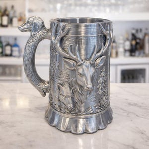 A professional collage showcasing over 20 unique 3D printable STL models for beer mugs and can holders. The image features high-detail designs including a horned Minotaur with gold accents, a gothic skull wearing aviator goggles, and a steampunk gas mask style tankard with copper pipes. The background displays various mythical, viking, and dark fantasy themed mugs in metallic silver and bronze finishes. Large yellow and blue 3D text in the center reads '20+ Can Holder & Beer Mug STL'.