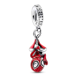 May include: A silver charm with the word "SPIDERMAN" engraved on the top. The charm features a red and silver Spider-Man figure hanging upside down. The figure has a red body with a black web pattern and white eyes.