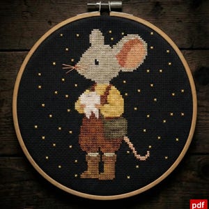 May include: Cross-stitch embroidery of a mouse holding a tooth, set in a wooden hoop. The mouse wears a yellow shirt, brown pants, and boots, against a black background with gold star accents. The design is a charming, handcrafted piece.