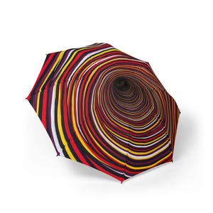 Pode incluir: Um guarda-chuva dobrável com um padrão circular concêntrico vibrante. O design consiste em anéis alternados em tons de vermelho profundo, amarelo brilhante, preto, branco e roxo escuro, irradiando a partir do ponto central da cobertura.