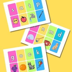 以下が含まれることがあります： カラフルな背景とイラストが特徴の教育用フラッシュカード。各カードには文字と、リンゴ、ペン、犬などの対応する画像が表示されています。これらのカードは、早期学習と読み書き能力のために設計されています。