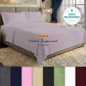 May include: A light purple bed sheet set featuring two matching pillowcases and a flat sheet. The text on the image reads 100% MICROFIBRE, PREMIUM, Hotel Inspired, and TOP LAYER. A colour palette of eight additional solid colour options is shown below.
