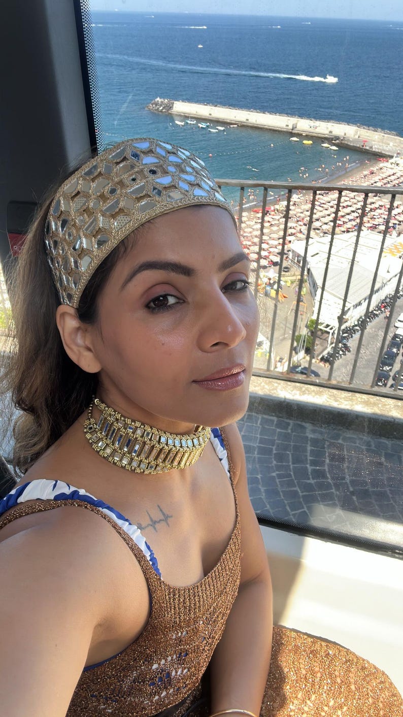 .	Relaxing beach shot highlighting the statement mirror work headband and jewelry ensemble