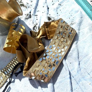 .	Side angle of embroidered headband under a beach umbrella, perfect for summer styling