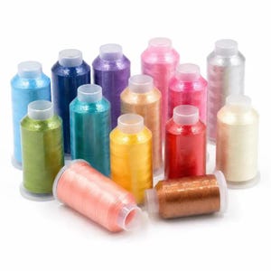 Op de afbeelding: Een verzameling van veertien cilindrische klossen borduurgaren in diverse levendige kleuren, waaronder blauw, groen, paars, roze, geel, rood, oranje, bruin en wit. Elke klos is voorzien van een doorzichtige plastic dop aan de boven- en onderkant.