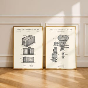 May include: Two framed vintage patent prints displaying detailed illustrations of early movie cameras. The prints, in gold frames, showcase technical drawings from the United States Patent Office, adding a touch of historical charm to any room.