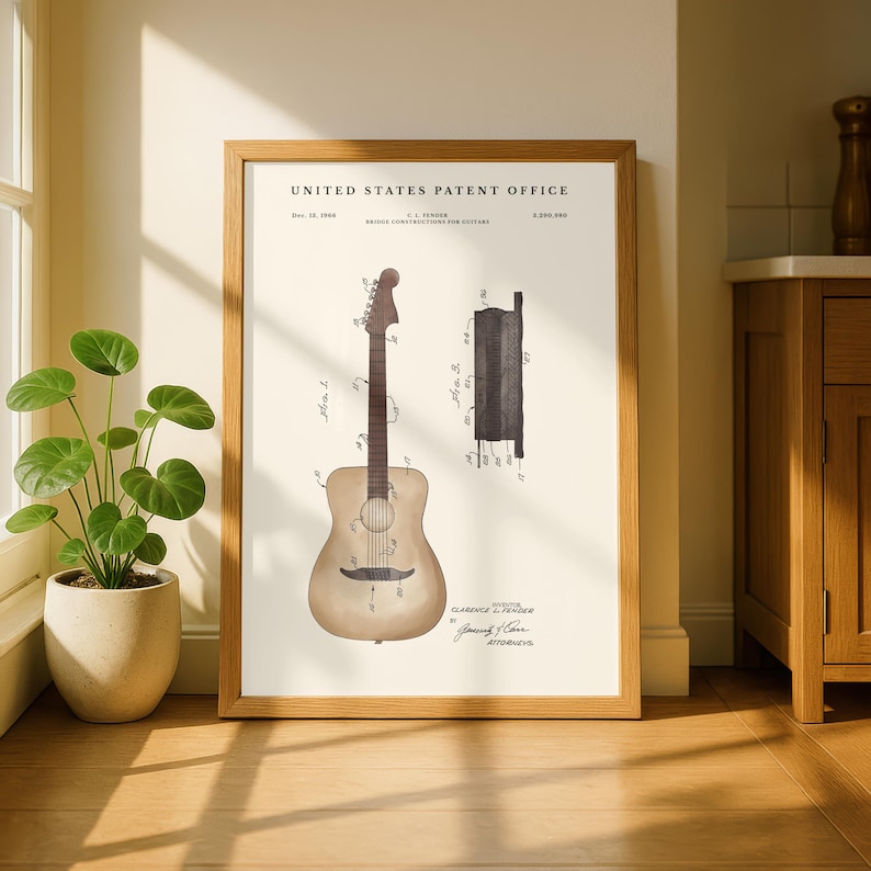 May include: Framed print of a guitar patent from the United States Patent Office. The print features a detailed illustration of a guitar and its components, with technical drawings and text. The frame is made of light brown wood.