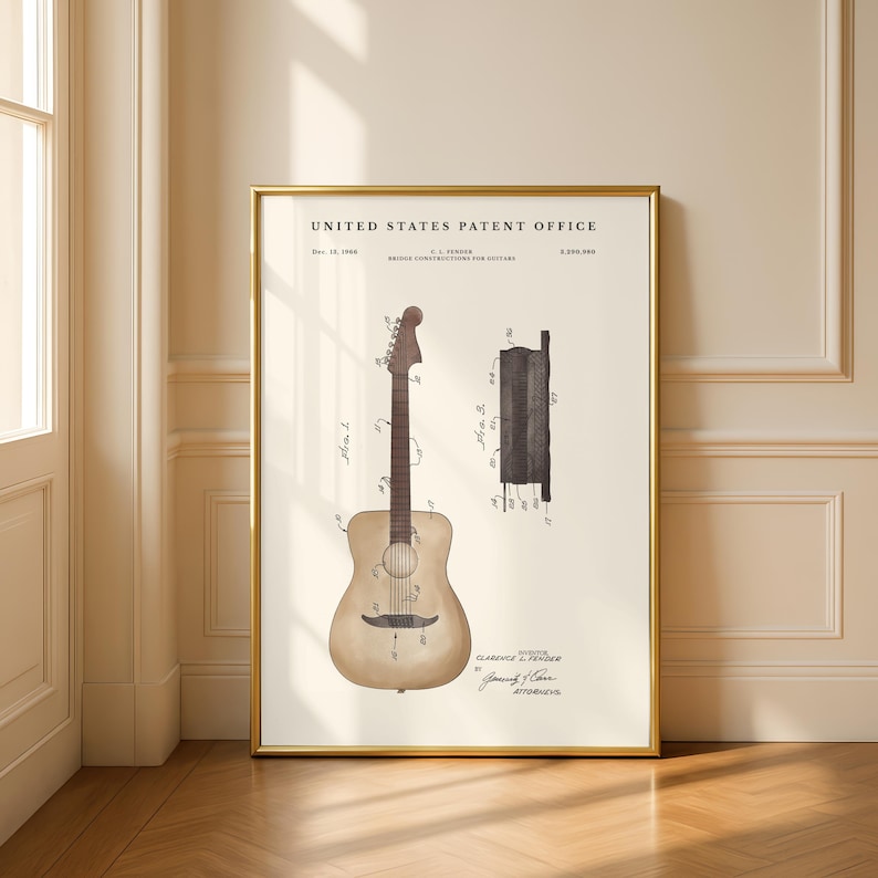 May include: A framed vintage patent print of a guitar. The print features a detailed illustration of a guitar and its components, with technical drawings and text. The frame is gold, and the background is off-white.