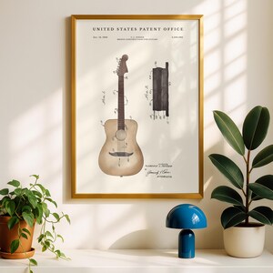 May include: A framed print of a guitar patent from the United States Patent Office. The print features a detailed illustration of an acoustic guitar and its bridge construction, with technical annotations and the inventor's signature. The frame is gold.