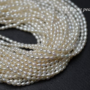 Peut inclure: Gros plan sur une grande collection de perles blanches crémeuses de forme ovale. Les perles sont en vrac et semblent être enfilées ensemble, créant un effet de cascade. Le texte "E Loose pearl" est visible en haut à droite.