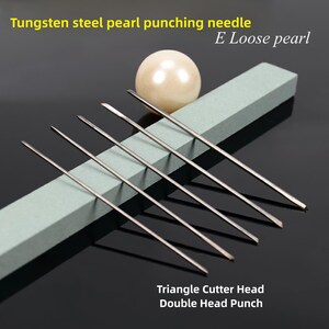 May include: Set of seven tungsten steel pearl punching needles with triangle cutter heads. The needles are arranged on a gray rectangular surface with a white pearl next to them. The text "E Loose pearl" and "Triangle Cutter Head Double Head Punch" are visible in the image.
