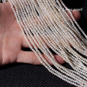 Puede incluir: Una hebra de perlas de agua dulce blancas, de aproximadamente 2-3 mm de tamaño, dispuestas en forma de abanico. Las perlas están enhebradas en un hilo fino y están listas para ser utilizadas en la elaboración de joyas.