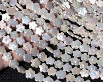 Peut inclure: Un brin de perles blanches en forme de fleur. Les perles sont enfilées sur un fil transparent et disposées en cascade.