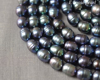 May include: Close-up of a collection of dark, oval-shaped pearls with a lustrous, iridescent sheen. The pearls display a range of colors, including black, green, and purple. The text "E Loose pearl" is visible in the upper right corner.