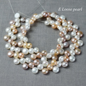 Könnte beinhalten: Eine Schnur loser Perlen in Weiß-, Creme- und Rosatönen. Die Perlen sind kreisförmig angeordnet und bilden ein wunderschönes und elegantes Ensemble. E Lose Perle.