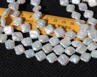 Peut inclure: Des perles baroques blanches iridescentes, de forme carrée, sont enfilées. Une règle jaune avec des marques noires et des caractères chinois est en arrière-plan. Les perles ont un éclat brillant. L'image est sur une surface noire.