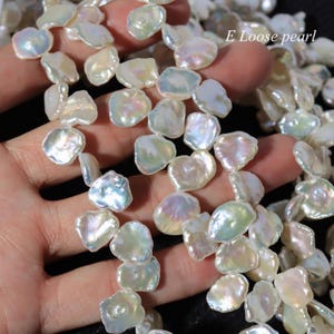 May include: Close-up of iridescent, irregular-shaped pearls. The pearls have a lustrous, pearlescent sheen with hints of pink, green, and blue. The text "E Loose pearl" is visible in the upper right corner. These pearls are ideal for jewelry making.