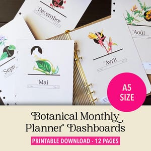 May include: A set of A5 size botanical monthly planner dashboards featuring twelve pages with white paper, gold ring binding, and illustrations of flowers and plants labeled with months in French, English, and Spanish text such as Mai, Avril, and Août.