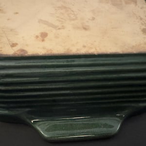 以下が含まれることがあります： 明るい茶色の内側を持つ、濃い緑色の長方形のベーキングディッシュ。 ディッシュは側面にリブのデザインがあり、片方の端にハンドルが付いています。 内部には使用の兆候が見られます。
