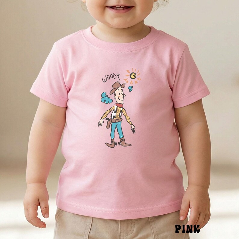 May include: Pink toddler t-shirt featuring a cartoon illustration of Woody from Toy Story. The design includes Woody's hat, outfit, and the word "Woody" in a handwritten font. The shirt is made of a soft material and is suitable for young children.