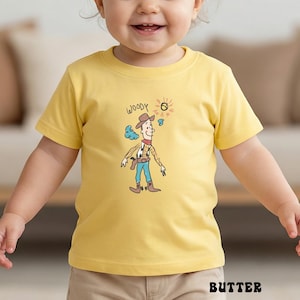 May include: A yellow t-shirt featuring a cartoon illustration of Woody from Toy Story. The design includes the word "WOODY" above the character, with a sun and cloud graphic. The shirt is made of a soft material and is suitable for children.