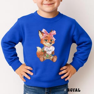 Peut inclure: Sweat-shirt bleu roi avec un renard de dessin anim&eacute; tenant un c&oelig;ur avec le mot "love". Le renard a une fourrure orange, un n&oelig;ud rose et porte une chemise hawa&iuml;enne. Le sweat-shirt est de couleur bleu roi uni.