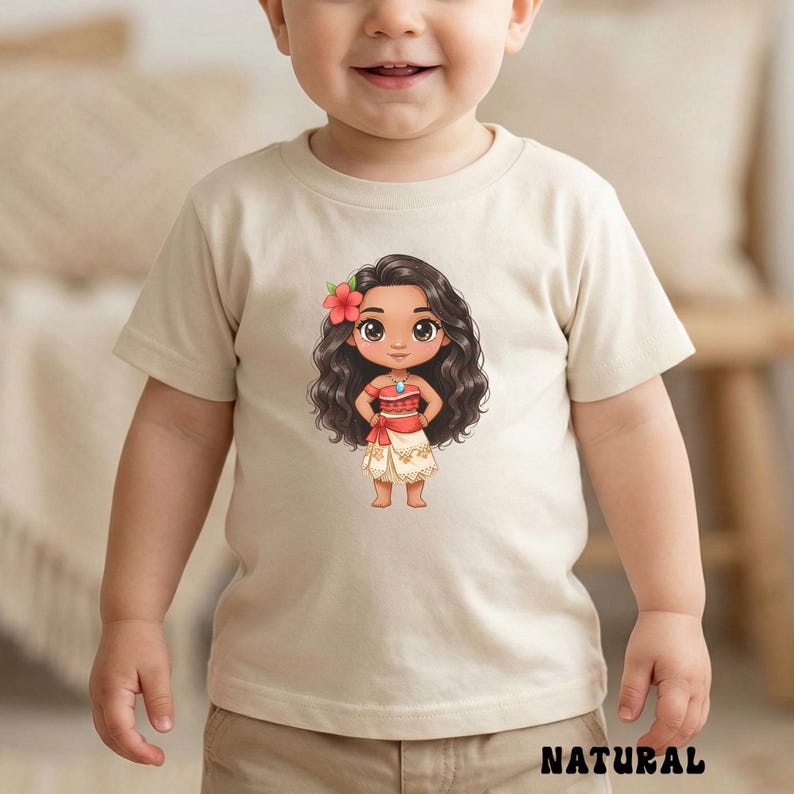 May include: A beige toddler t-shirt featuring a cartoon illustration of a Polynesian girl with long black hair, a red flower, and a red and white outfit. The word "NATURAL" is printed in black at the bottom of the shirt.