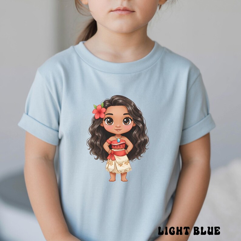 May include: Light blue t-shirt featuring a cartoon illustration of a character with long, wavy brown hair, a red flower, and a red and white outfit. The text "LIGHT BLUE" is printed at the bottom of the shirt.