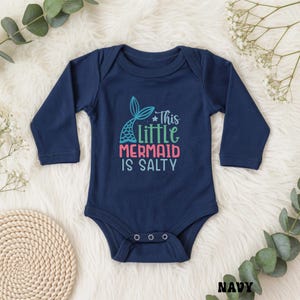 Puede incluir: Una taza de cer&aacute;mica blanca con un asa negra y el texto "But First, Coffee" en negro, con una fuente de estilo manuscrito. La taza est&aacute; sobre una superficie blanca.