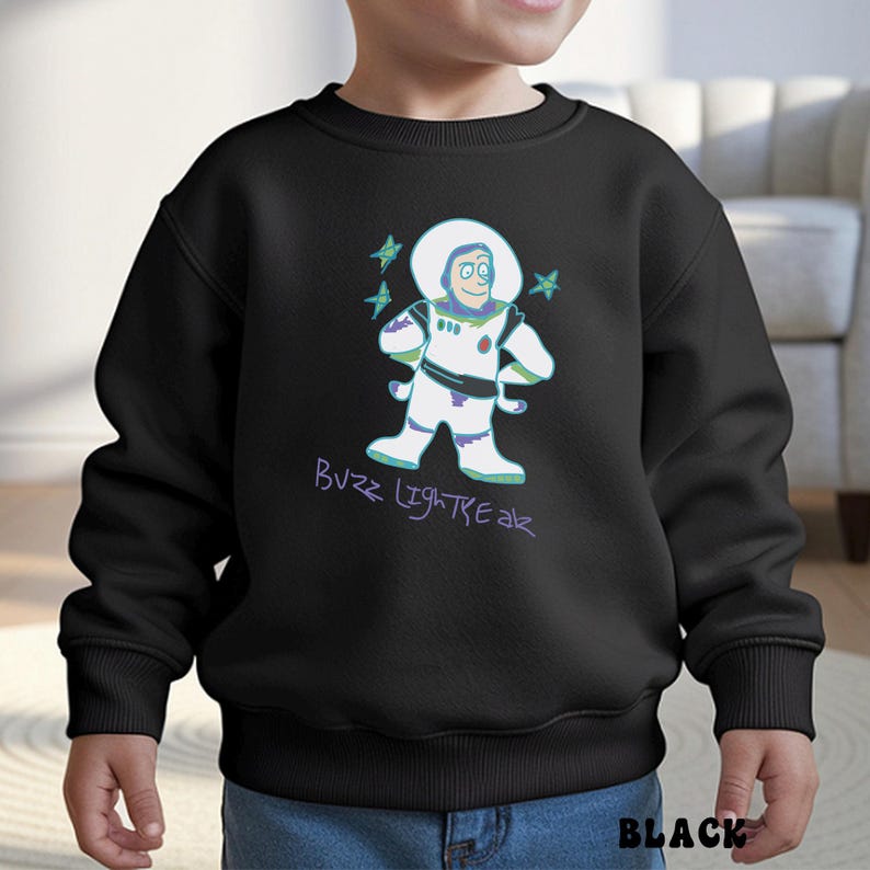 May include: Black sweatshirt featuring a cartoon illustration of Buzz Lightyear in a white spacesuit with green and purple accents. The text "Buzz Lightyear" is written in purple script below the character. The word "BLACK" is printed in white at the bottom.