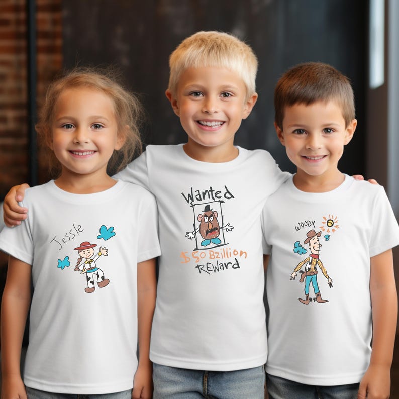 May include: Three children wearing white t-shirts with cartoon character designs. One shirt says "Jessie" with a drawing of a cowgirl. Another says "Wanted" with a Mr. Potato Head drawing. The third says "Woody" with a cowboy drawing.