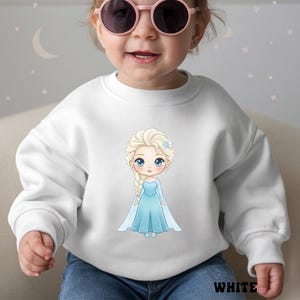 Puede incluir: Sudadera blanca con una ilustraci&oacute;n de dibujos animados de una princesa con un vestido azul. La princesa tiene el pelo rubio y un accesorio floral azul. La palabra "WHITE" est&aacute; impresa en la parte inferior.