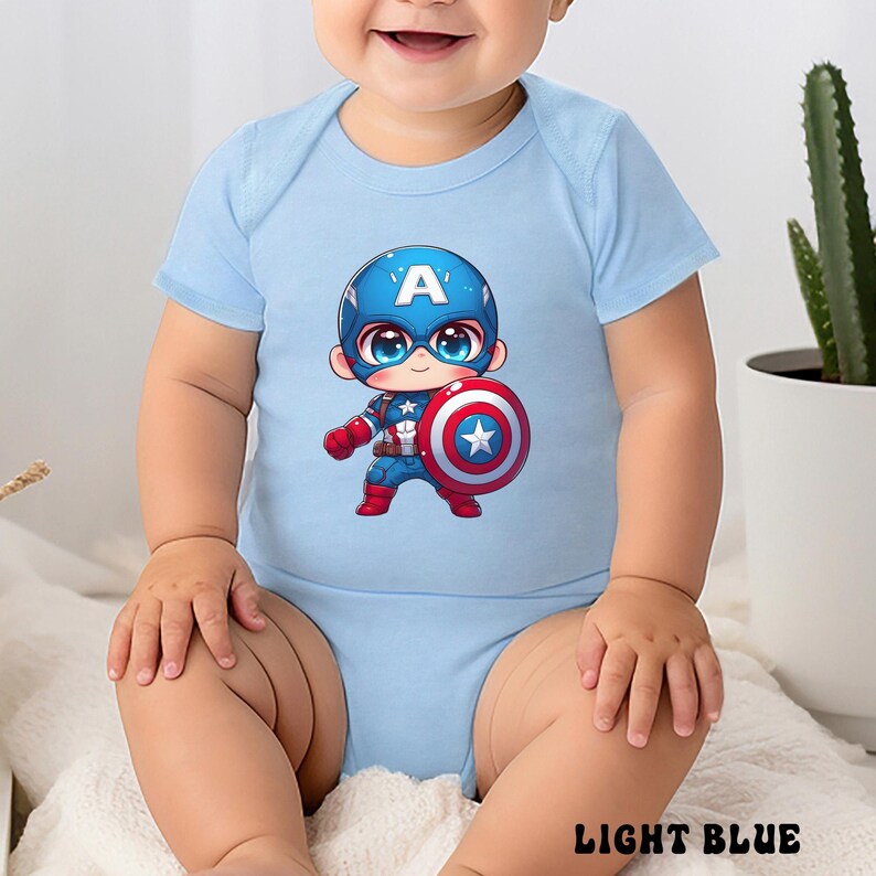 Op de afbeelding: Lichtblauwe babybody met een Captain America cartoon ontwerp. De illustratie toont Captain America met zijn schild. De body heeft korte mouwen en de tekst "LIGHT BLUE" staat onderaan.