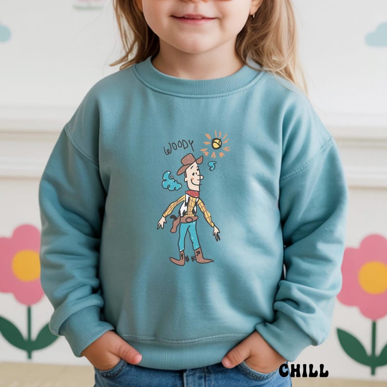 May include: A teal sweatshirt featuring a cartoon illustration of Woody from Toy Story. The design includes Woody in his cowboy attire, a sun, and the word "WOODY" above the character. The word "CHILL" is printed at the bottom.