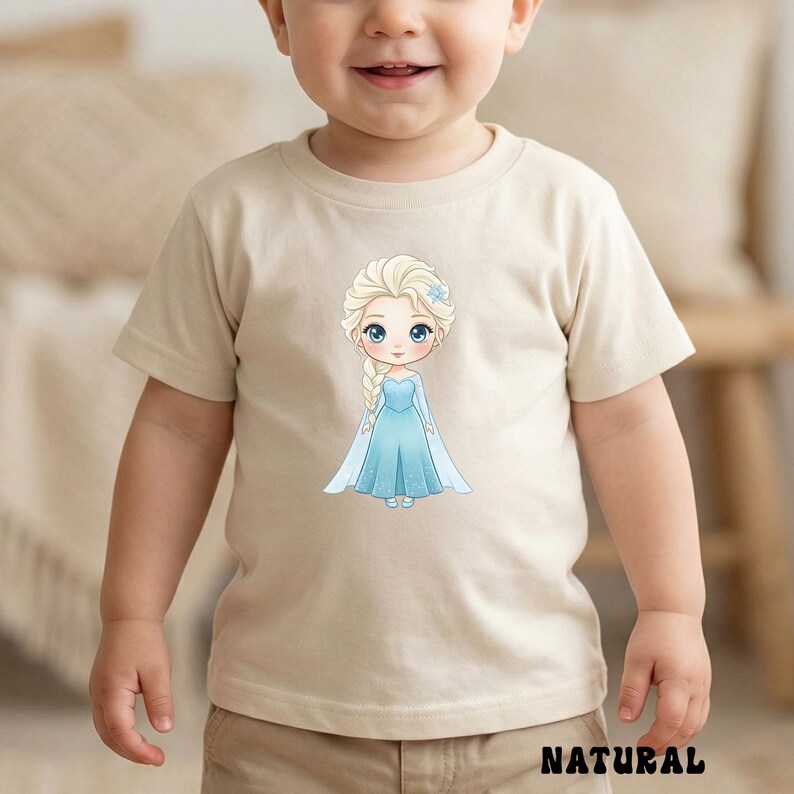 Puede incluir: Camiseta beige con una ilustraci&oacute;n de dibujos animados de una princesa con un vestido azul, trenza rubia y flor azul. La palabra "NATURAL" est&aacute; impresa en negro en la parte inferior de la camiseta.