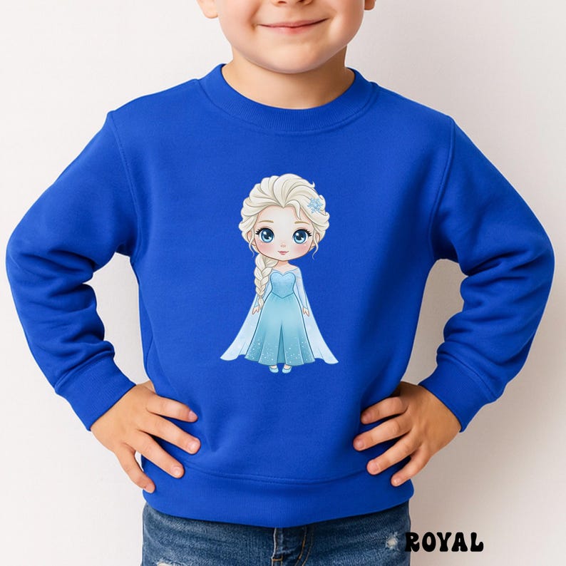Puede incluir: Sudadera azul real con una ilustraci&oacute;n de dibujos animados de una princesa con un vestido azul y cabello rubio, adornada con una flor azul. La palabra "ROYAL" est&aacute; impresa en la parte inferior. Ropa para ni&ntilde;os.