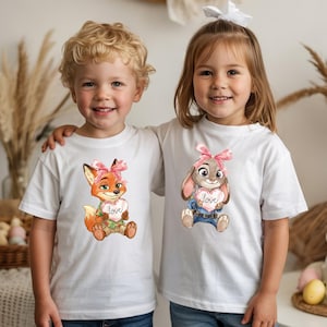 Peut inclure: Deux enfants portant des t-shirts blancs. L'un pr&eacute;sente un renard de dessin anim&eacute; tenant un c&oelig;ur avec le mot "love", l'autre un lapin tenant un c&oelig;ur avec "love". Les deux personnages ont des n&oelig;uds roses. Les t-shirts sont pour enfants.