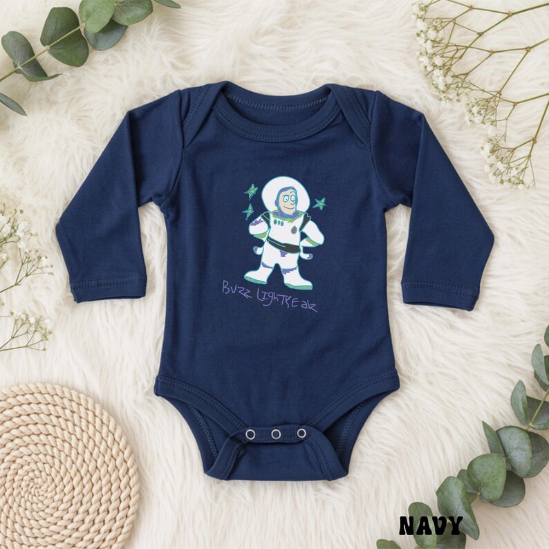 May include: Navy blue baby bodysuit with long sleeves. The front features a cartoon illustration of Buzz Lightyear in a white spacesuit with green and purple accents. The text "Buzz Lightyear" is written below the character in a playful font.