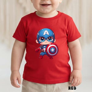 Op de afbeelding: Rood T-shirt met korte mouwen met een cartoonafbeelding van Captain America. De afbeelding toont Captain America die zijn schild vasthoudt. Het woord "RED" staat onderaan het shirt.