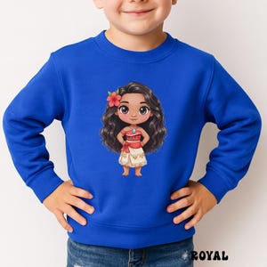 May include: Royal blue sweatshirt featuring a cartoon illustration of a Polynesian girl with long, wavy black hair, a red flower, and a red and white outfit. The word "ROYAL" is printed in black at the bottom right.