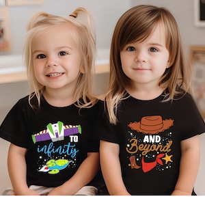 May include: Two young children wearing black t-shirts. One shirt says "To infinity" with a spaceship graphic. The other shirt says "And Beyond" with a cowboy hat, boot, and bandana graphic. Both shirts have colorful designs.